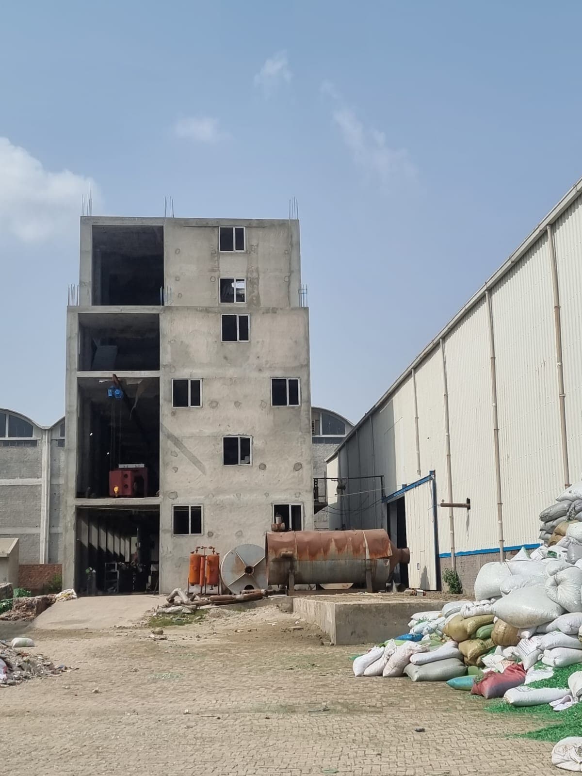 Multi-story melt spinning tower and feedstock handling facility